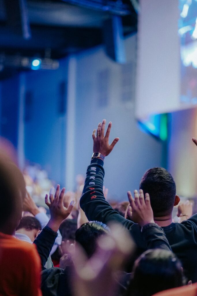 A lively crowd raising hands during an indoor worship service, full of spirituality.